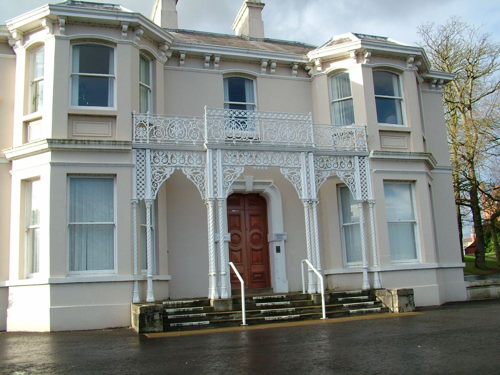 Two-storey Victorian villa with bay windows and an ornate white cast-iron veranda and balcony over the front door